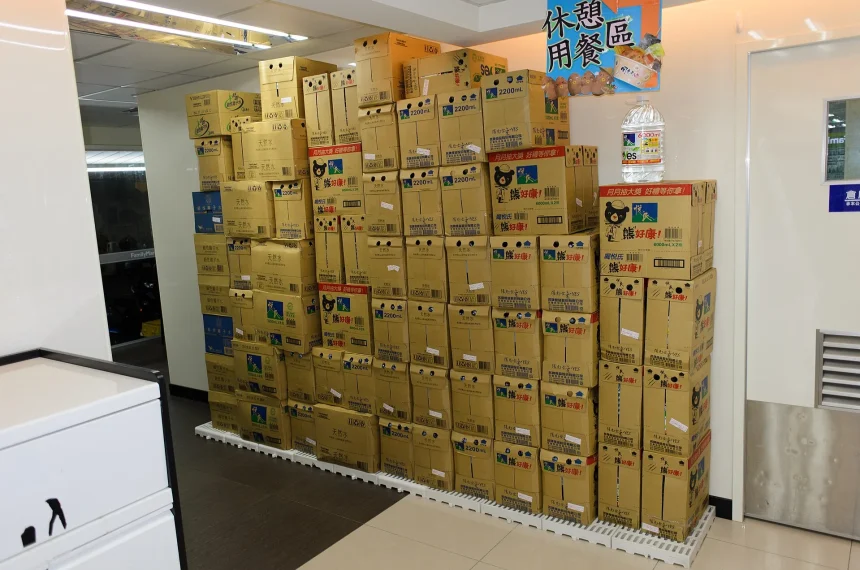 Stacked boxes of bottled water inside a convenience store - Bottled Water Brands Keep Winning Shelves Despite Plastic Fears