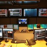 A cybersecurity analyst monitors multiple screens showing network data and security alerts.